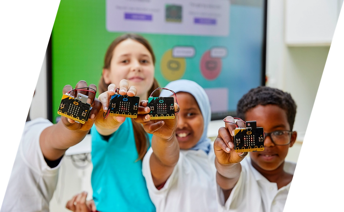 children in class smiling and holding micro:bits